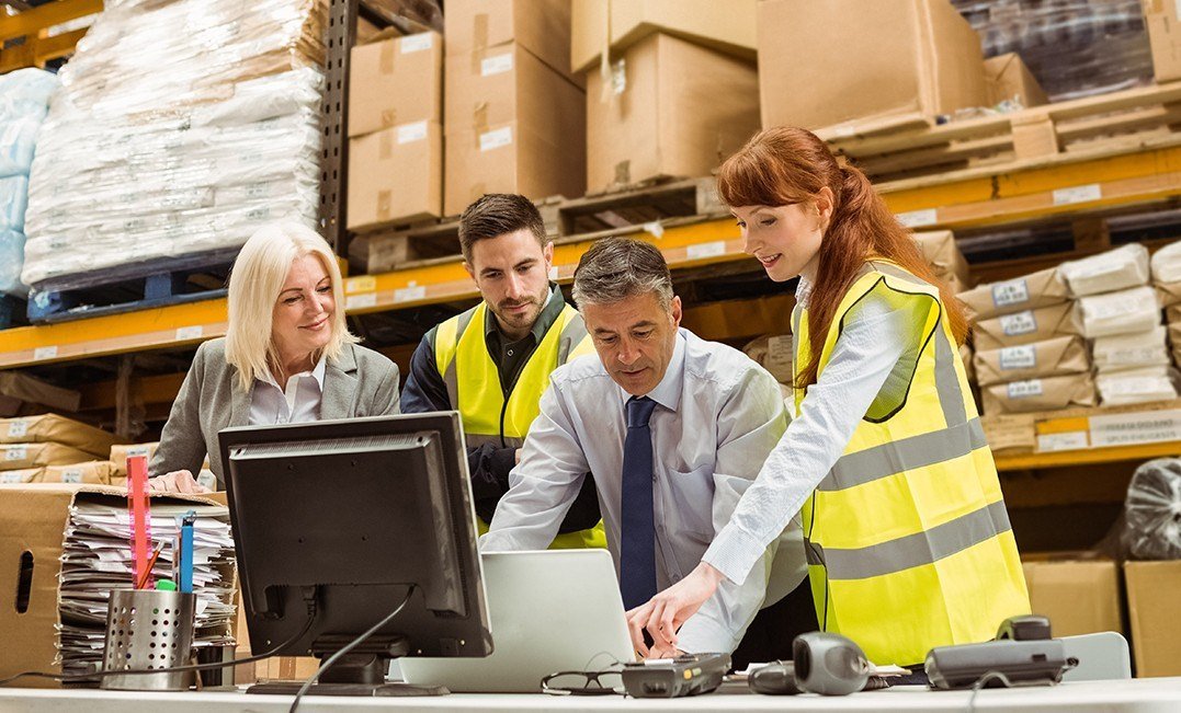 three people in safety vests looking at a computer