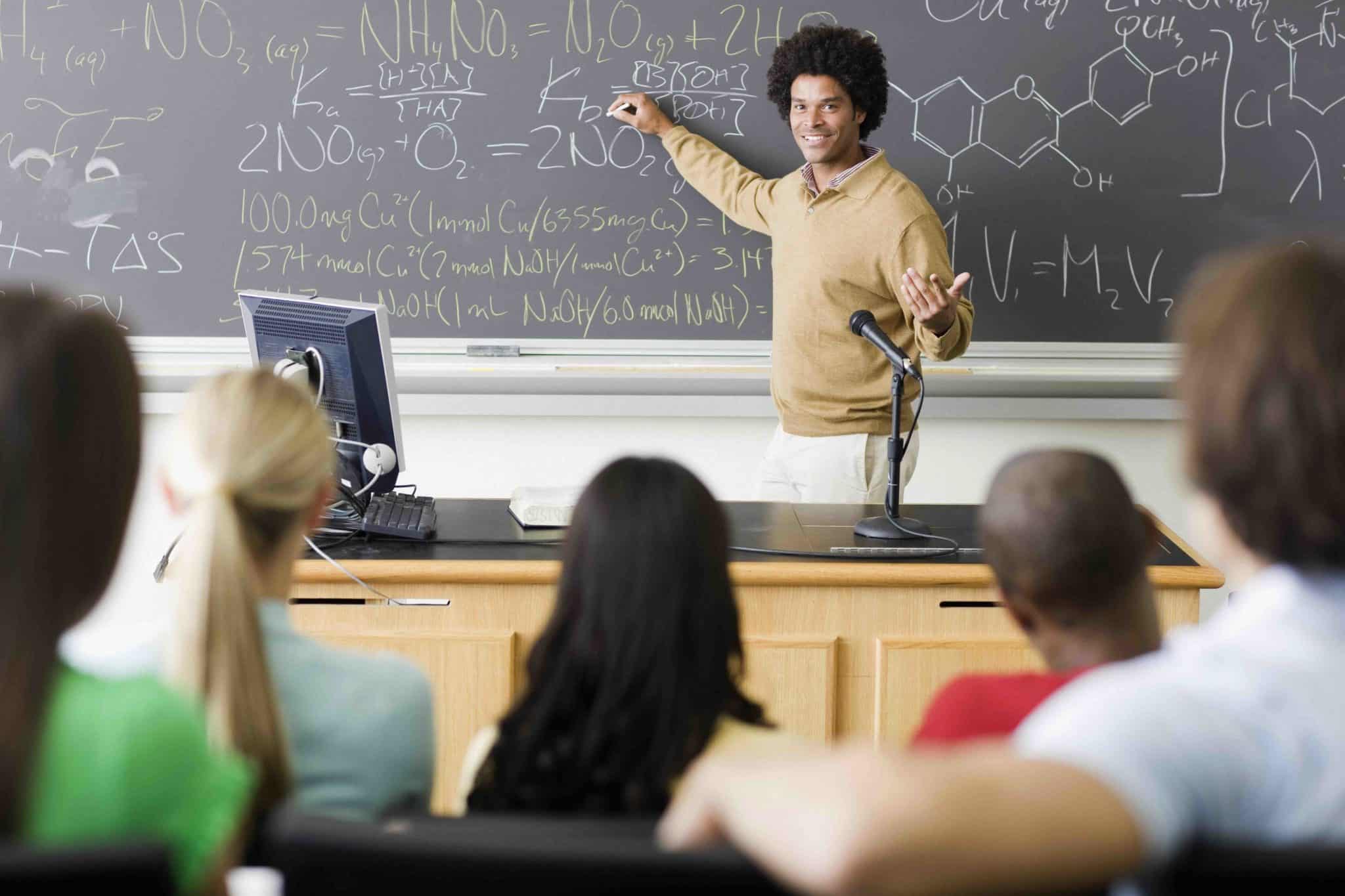 a man standing in front of a blackboard giving a lecture