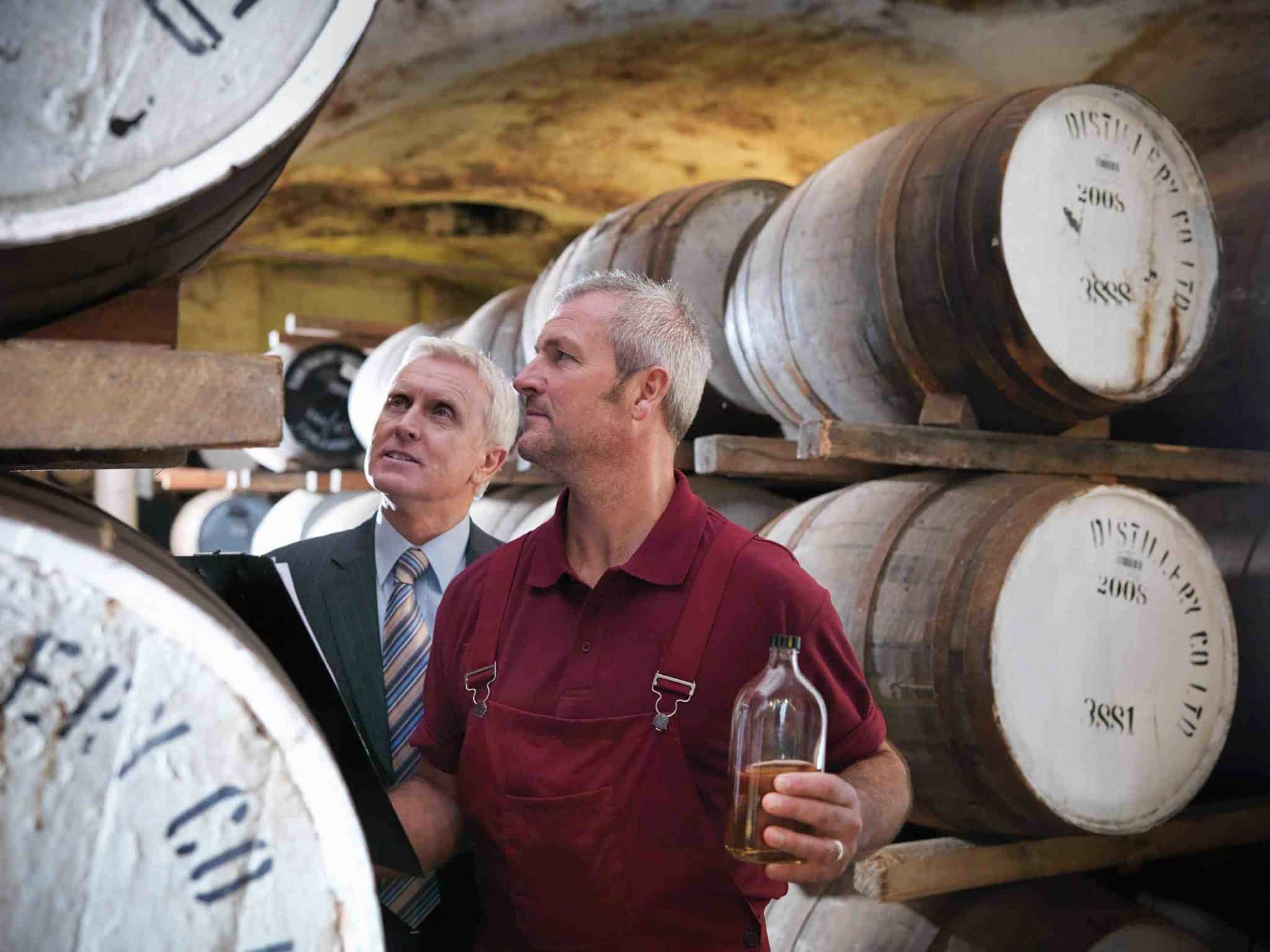 two men standing next to each other holding wine glasses