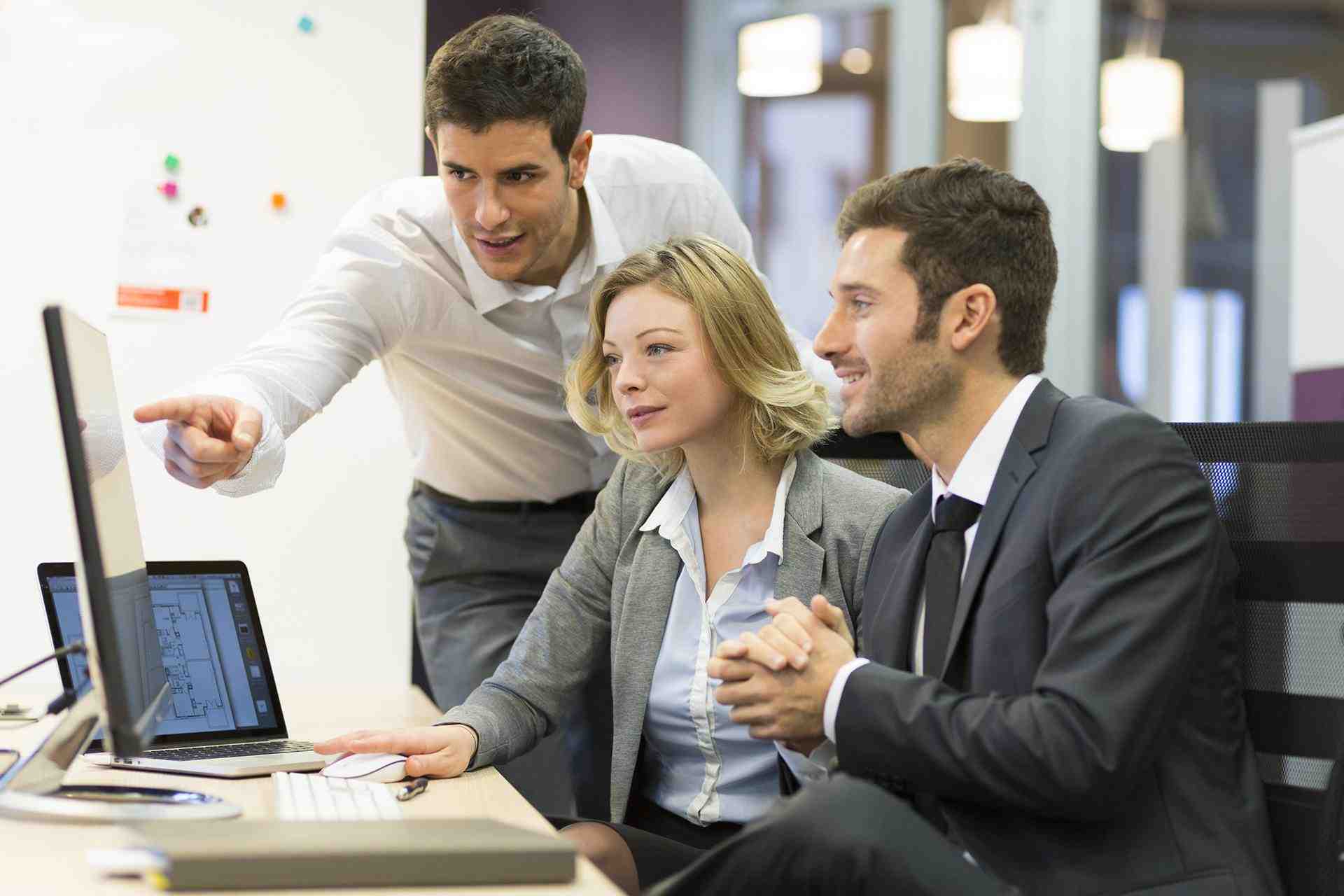 two men and a woman looking at a computer screen