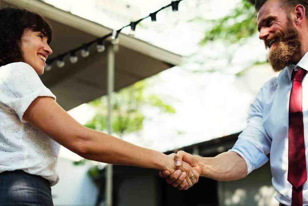 a man and woman shaking hands in front of a tent