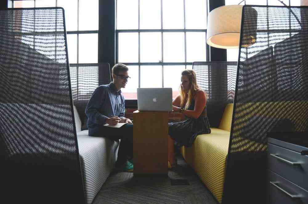 a man and woman sitting at a table with a laptop