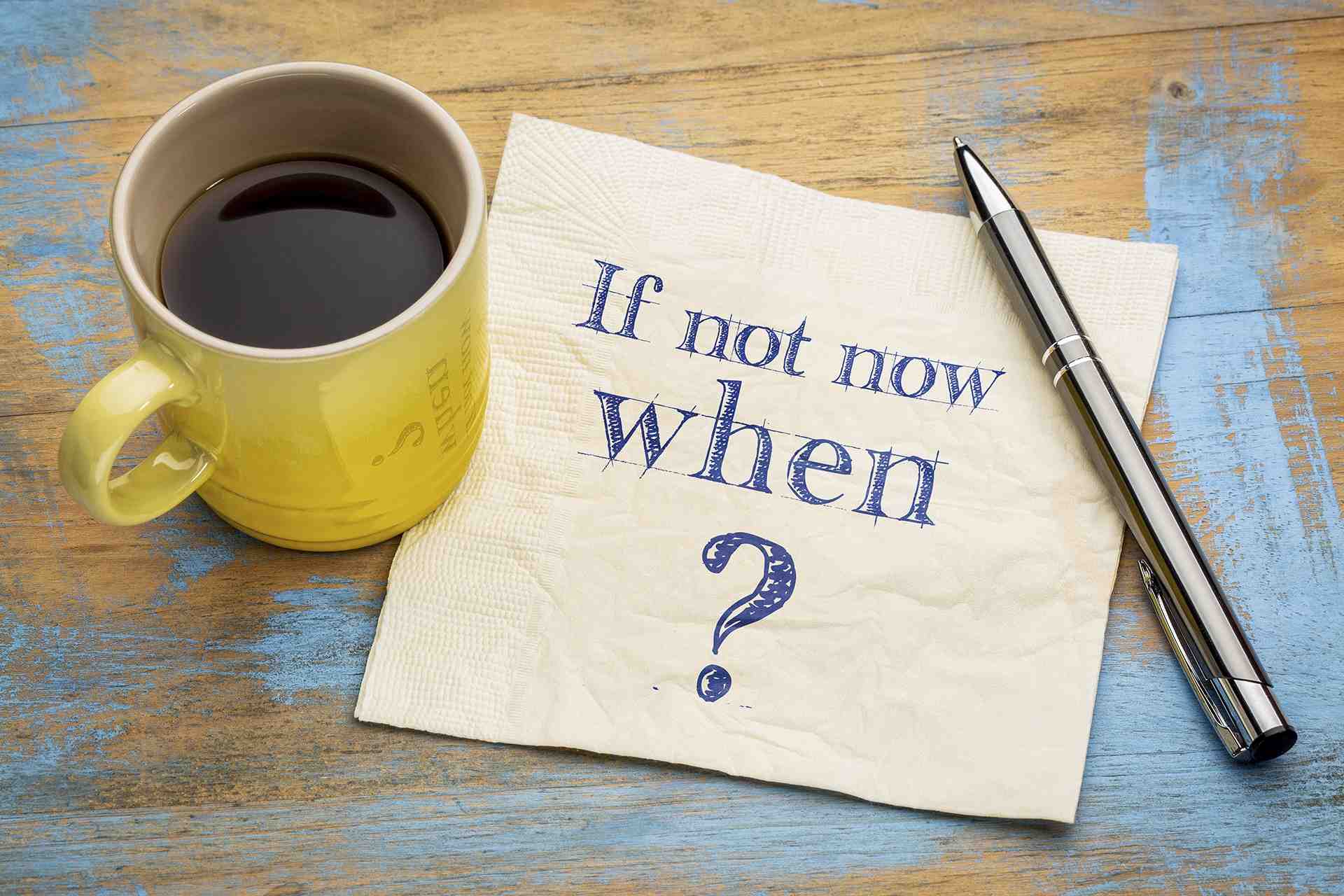 a napkin with the words if not now when on it next to a cup of coffee