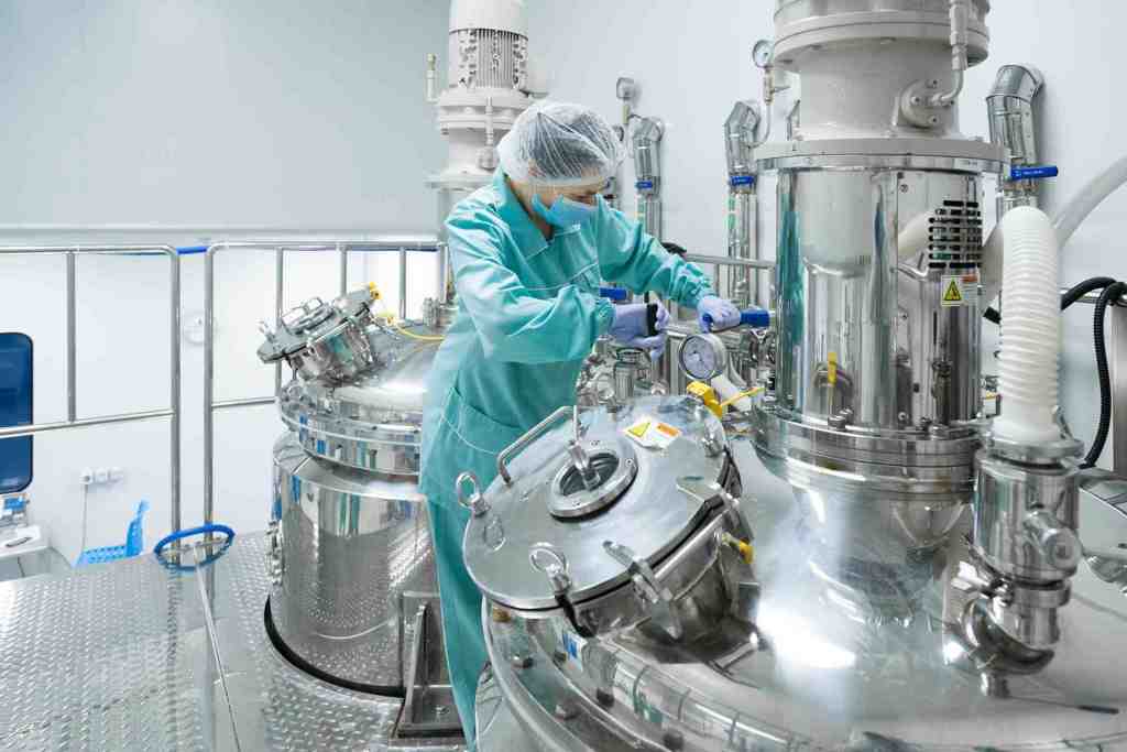 a person in a lab coat and gloves working on a machine