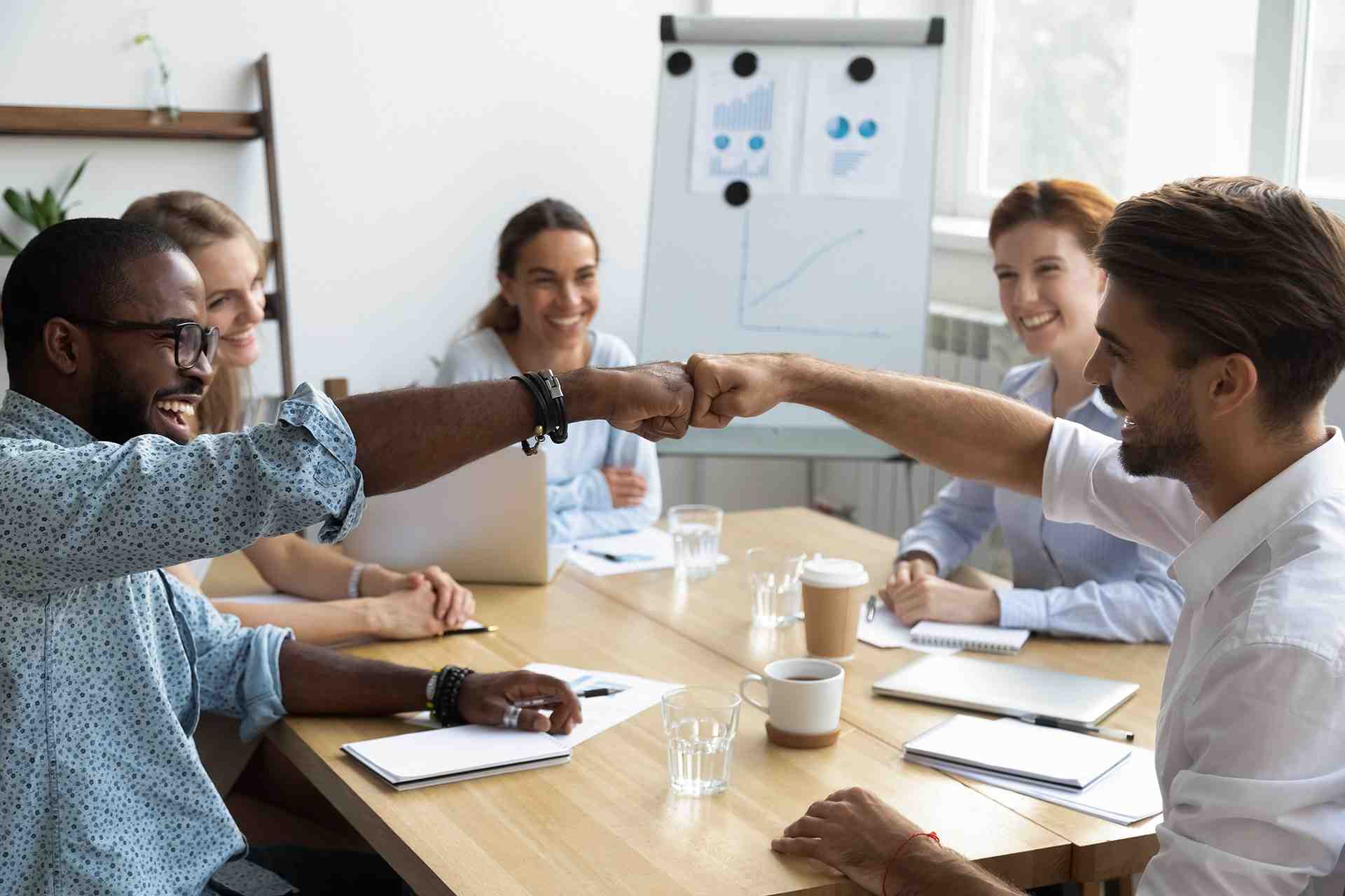 a group of people sitting around a table shaking hands