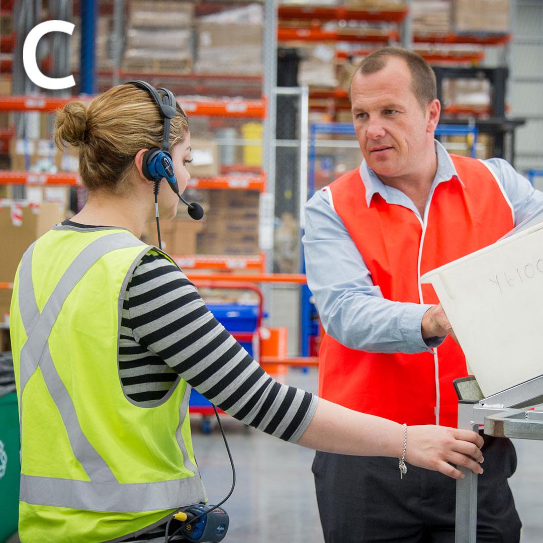 a man and a woman are talking to each other in a warehouse