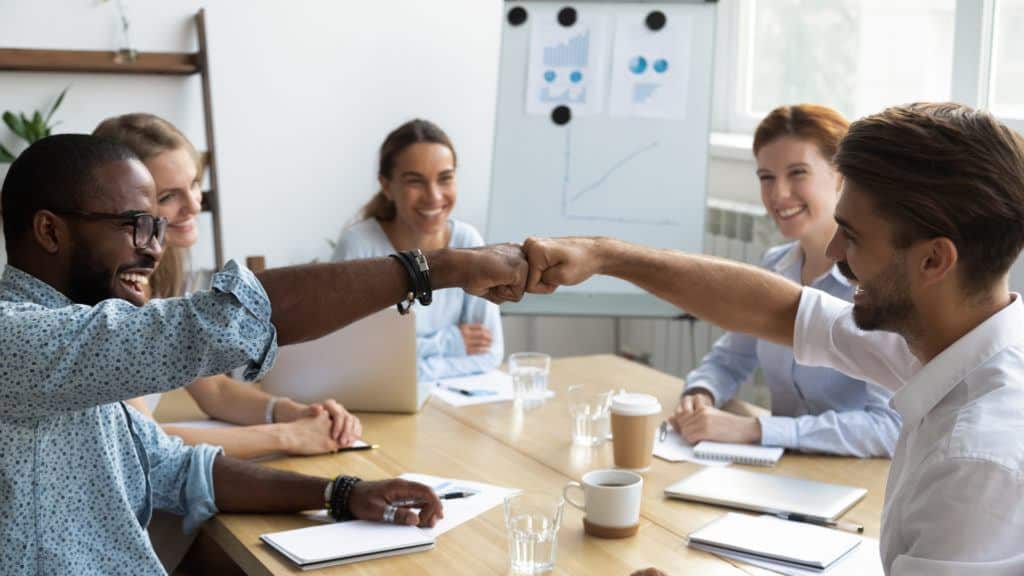 a group of people sitting around a table shaking hands