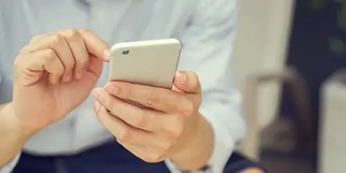 a man sitting down while looking at his cell phone