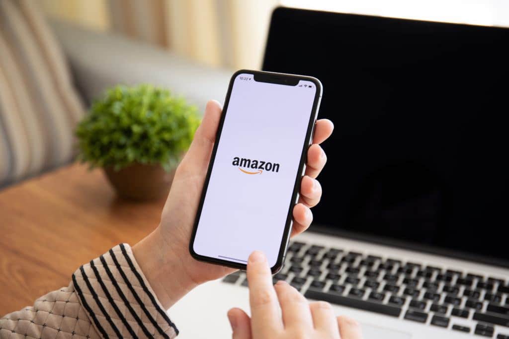 Woman holding iPhone X with Internet shopping service Amazon