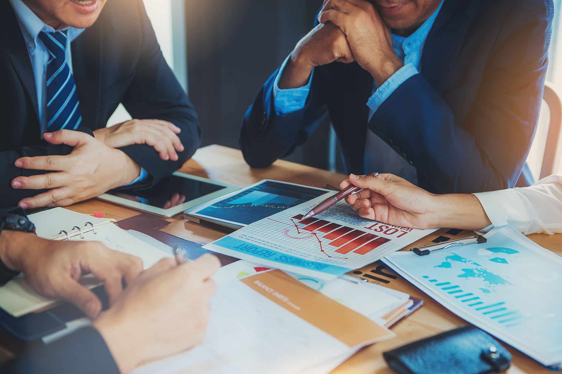 three people sitting at a table with papers and tablet computers