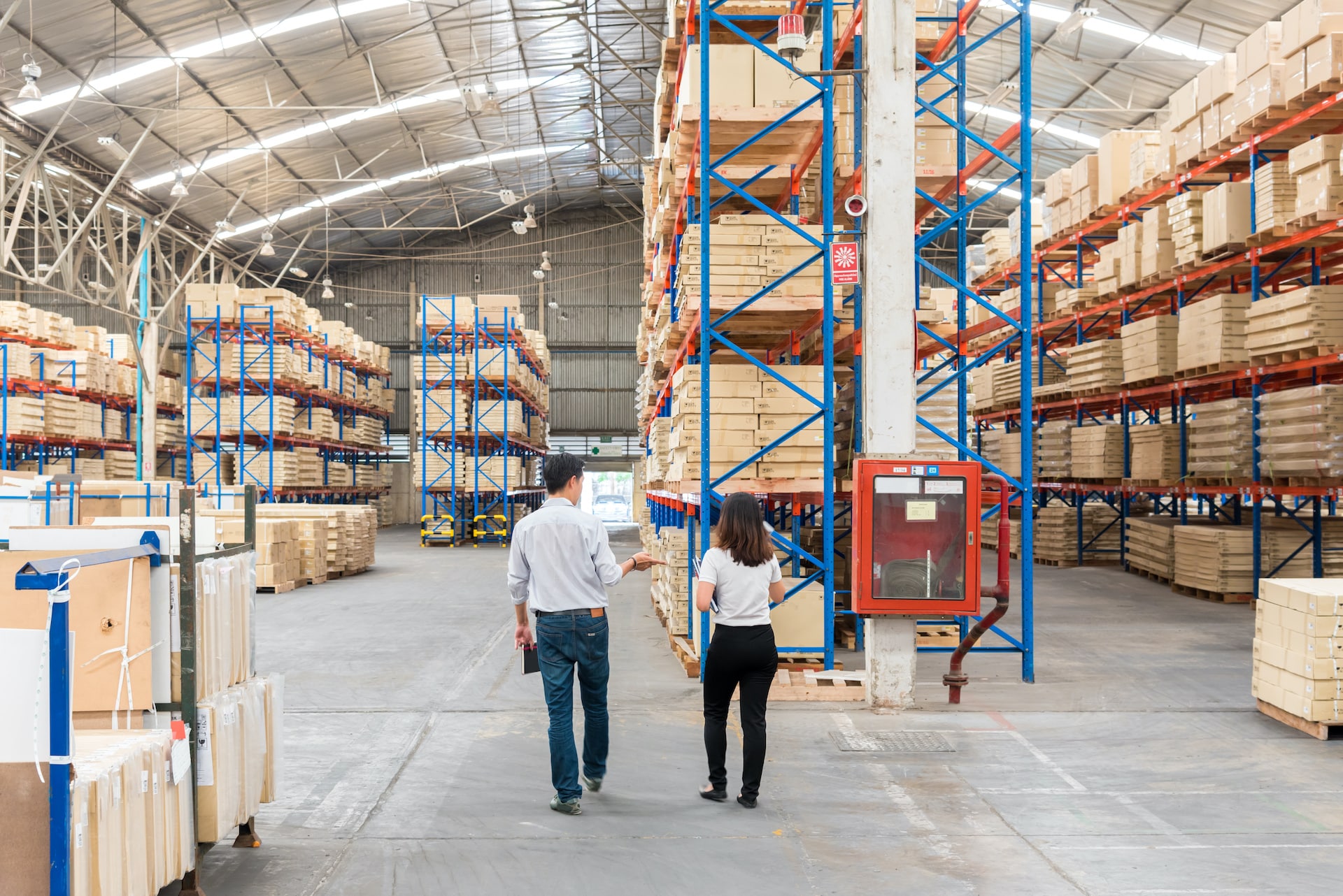 two people walking through a warehouse with boxes