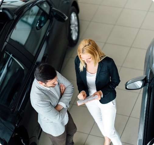 two people standing next to a car looking at something