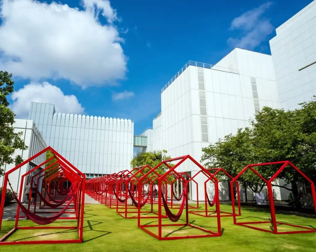 a group of red metal structures sitting on top of a lush green field