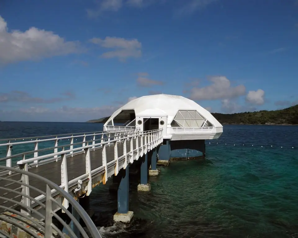 a white boat is docked at the end of a pier