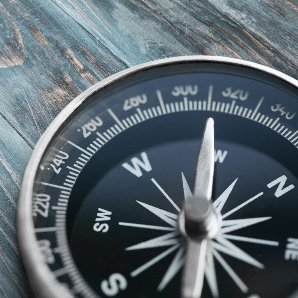 a close up of a compass on a wooden surface