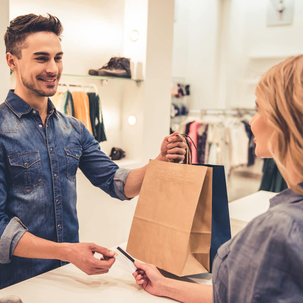 a man is handing a woman a brown paper bag