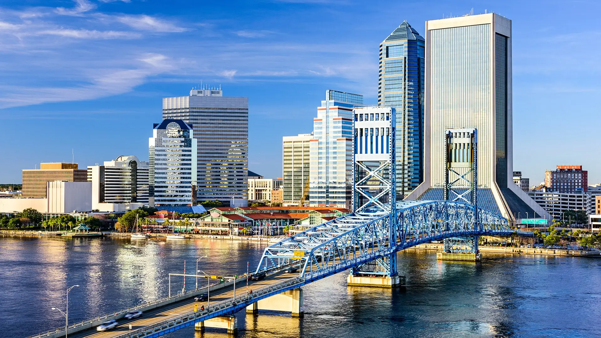 a blue bridge crossing over a river in front of tall buildings