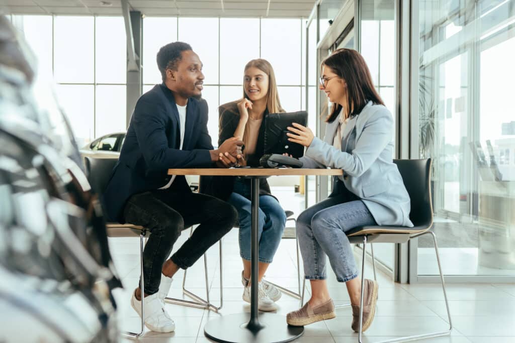 three people sitting at a table talking to each other