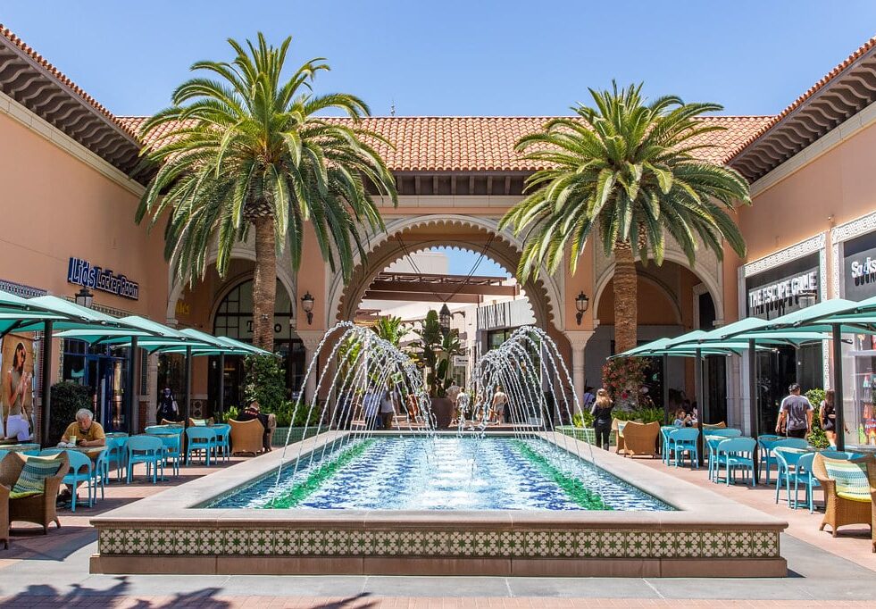 a fountain surrounded by palm trees in front of a building