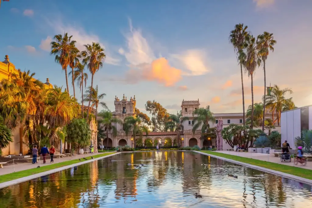 a pond surrounded by palm trees in front of a building