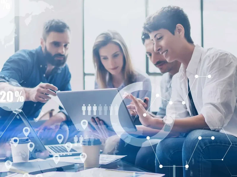 three people sitting on a couch looking at a tablet